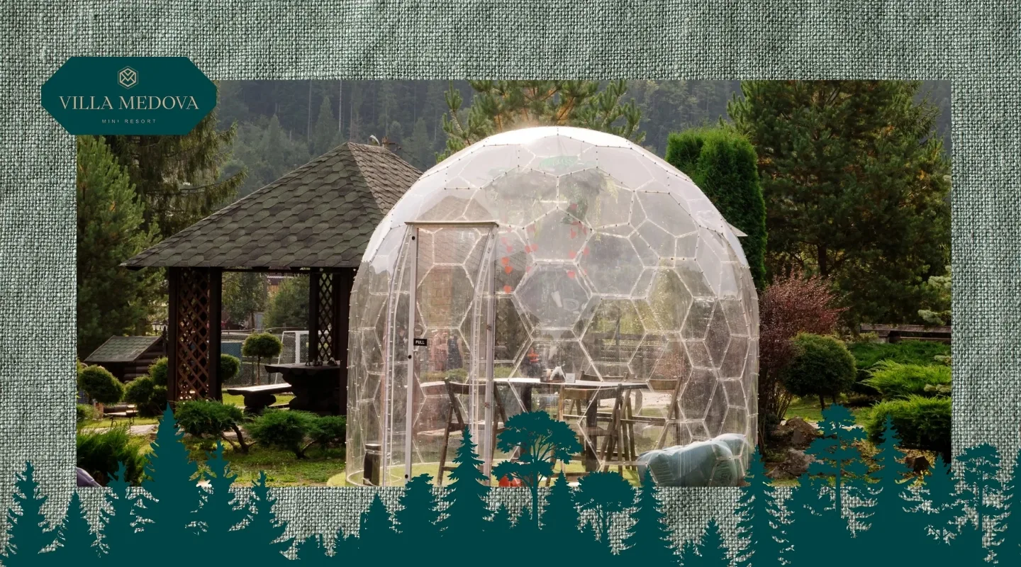 Hlempinh u Karpatakh vidpochynok u prozorykh heokupolakh pid zoryamy Geodesic glass dome and wooden gazebo in a landscaped garden with Villa Medova logo in the corner.